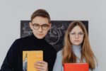 Dziewczyna i chłopak w okularach trzymający przed sobą książki do języka polskiego